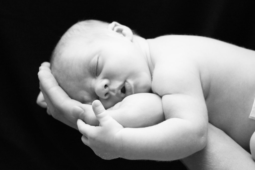 Baby lying on hand, black and white